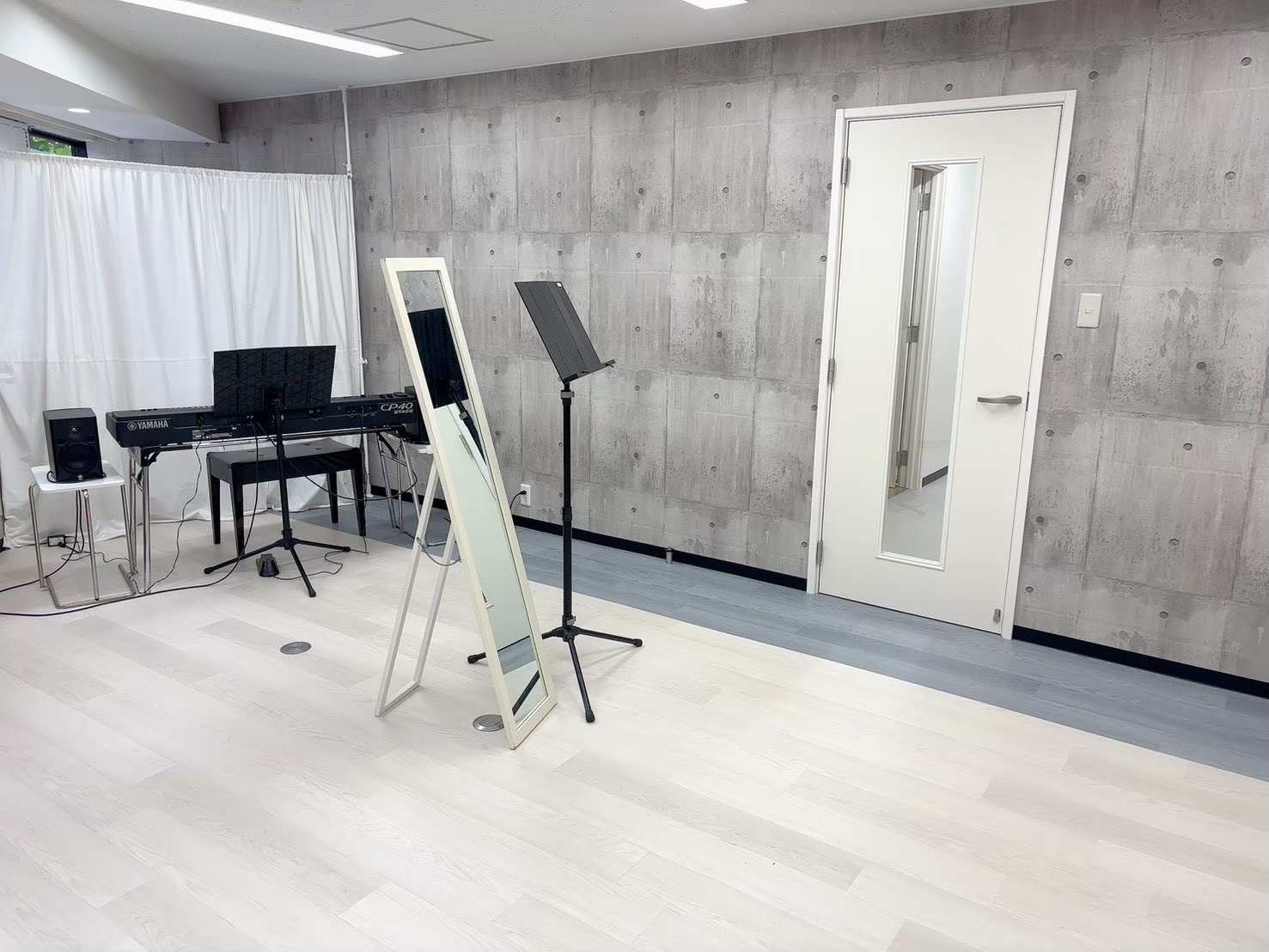 S&Sの広いレッスンスタジオ。鏡と電子ピアノ、譜面台が設置されている室内